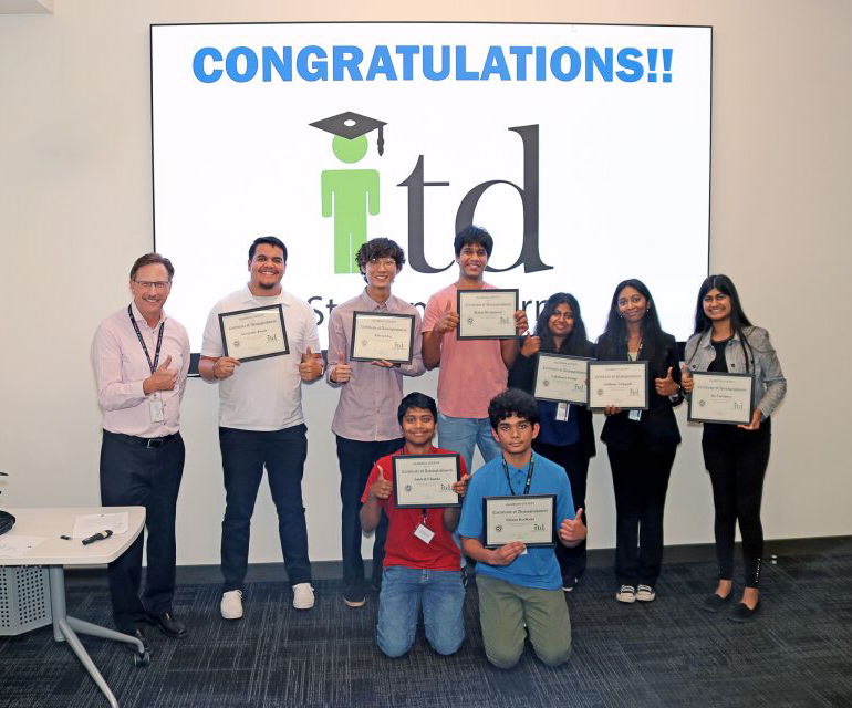 2023interns holding certificates in front of congratulations banner